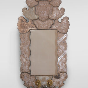A Venetian-style mirror with brass candle holders.