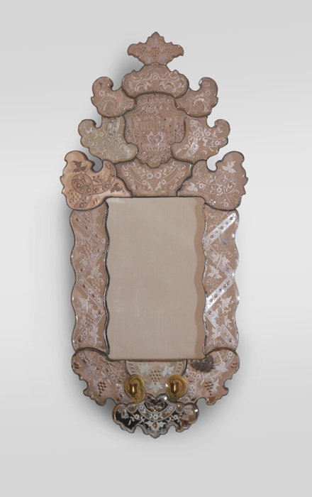 A Venetian-style mirror with brass candle holders.