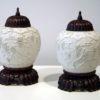 A fine pair of bisque overlay porcelain jars with rosewood covers and stands